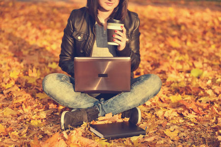 girl sitting on the leaves in the park. Vintage autumn photoの写真素材