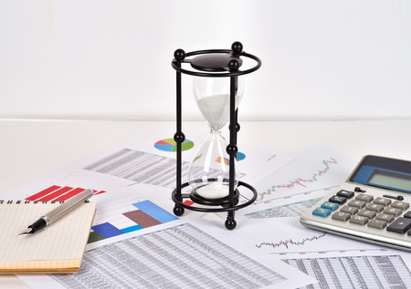 sandglass and financial and business charts and report on table