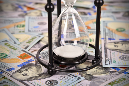 Black hourglass and many dollar bills, close upの写真素材