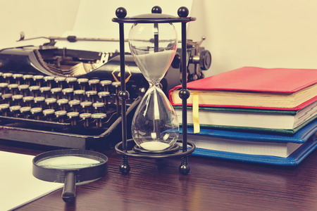 Hourglass, books and vintage typewriter on table. 
Vintage effectの写真素材