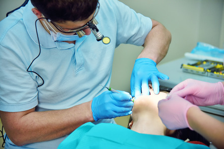dentist with assistant conducting an operation in the mouthの写真素材