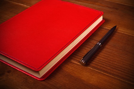 red leather diary and pen on wooden deskの写真素材