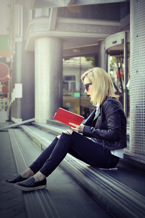 young hipster girl reading a red book. toned effectの写真素材
