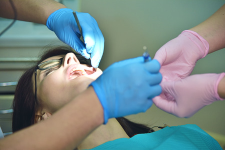 Professional dentist doing operation on female patient
