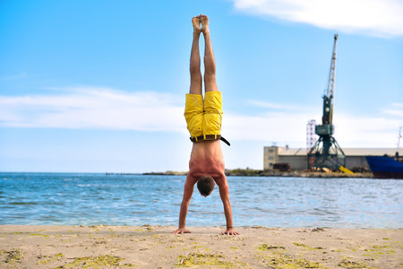 man doing yoga standing on hands. industrial harbor crane backgroundの写真素材