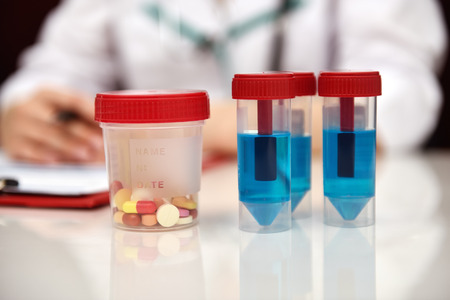 Woman Working In Clinic. Blue Sample And Tablet On table. Close Upの写真素材