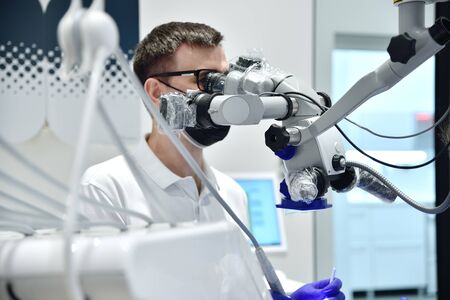 doctor in black mask using dental microscope in clinic. close up