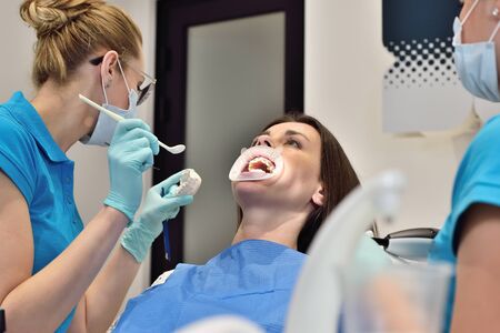 Dentist Woman And Assistant Installation Braces To The Patient In Dental Clinicの写真素材