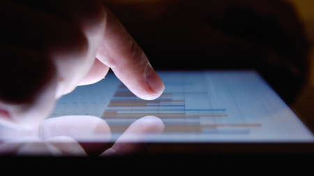 Trader touching digital tablet screen with growth of financial stock markets. Success and start up concept. Close upの写真素材