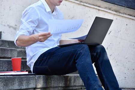 Man sitting on stairs and examines financial report. Business and financial success concept.