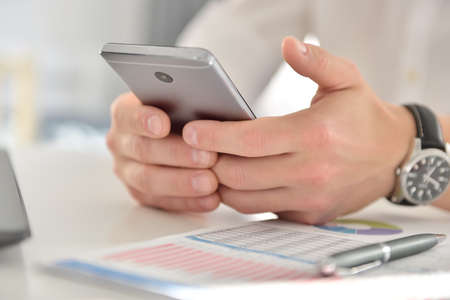 Businessman hand using mobile phone and analyzing business plan. Investment and financial concept.
