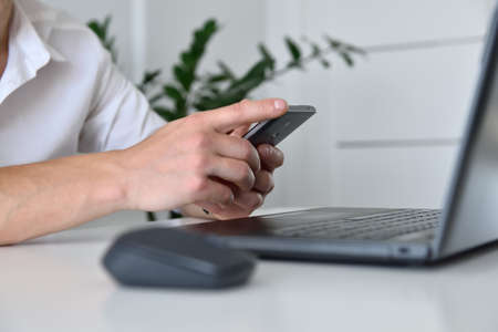 Businessman hand with mobile phone looking on business plan. Investment and financial concept. Close...