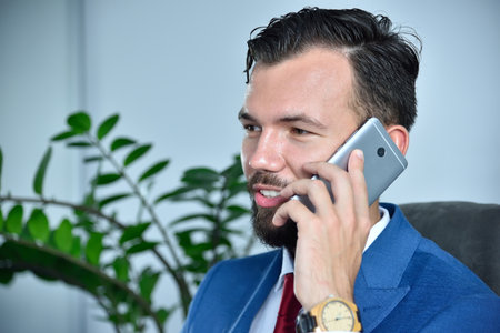 Young bearded businessman working in office and talking on mobile phone. Occupation and worker concept.の写真素材