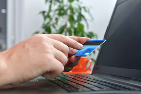 Man makes a purchase on internet and points his finger at the cvv code. Online payment and shopping concept. Close upの写真素材