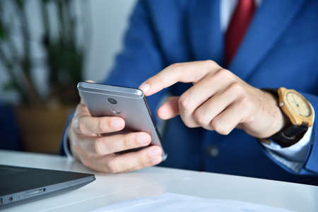 Businessman writes message on smart phone. Business and working concept. Close up