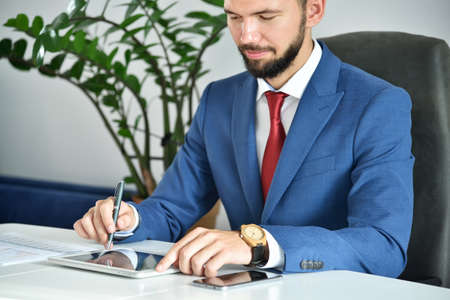 Businessman sitting in office and using digital tablet computer. Business and financial success concept.の写真素材