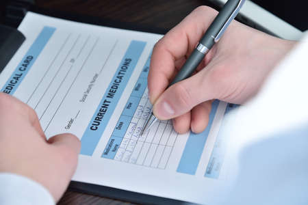 Doctor writing medical card to clipboard at hospital. Healthcare and medicine concept. Close up