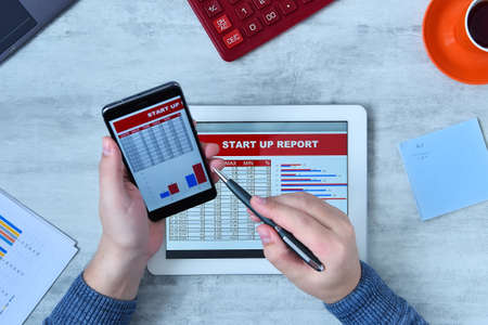 Office man using tablet computer and smartphone and checking stock market data. Success and startup...