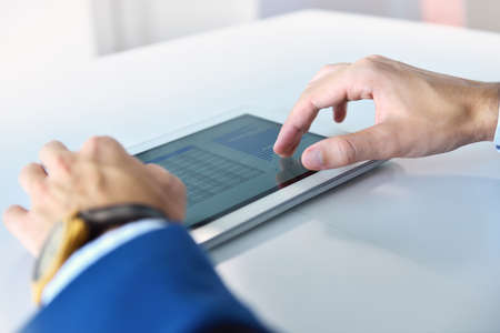 Businessman in suit using digital tablet with financial data and stock report. Business and...