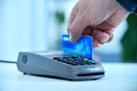 Close up of hand makes payment by blue credit card. Electronic money and shopping concept.の写真素材