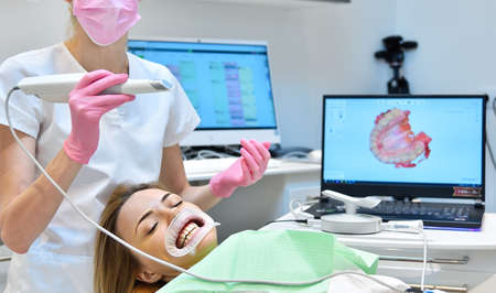 Woman having her teeth 3d scanned by professional dentist. Prosthodontics and stomatology concept.の写真素材