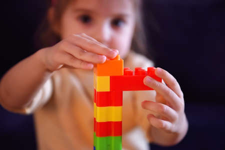 Close up of little child builds tower of colored plastic blocks. Concept of educational games and children development.の写真素材