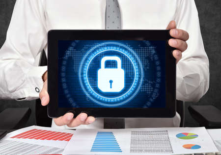 Businessman holding tablet computer and digital lock icon interface with circle binary numders and world map. Cyber security and digital protection concept.の写真素材