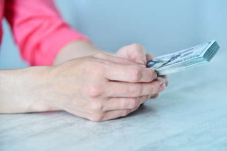 Businesswoman pink shirt counting dollars at table. Financial success and business concept. close up