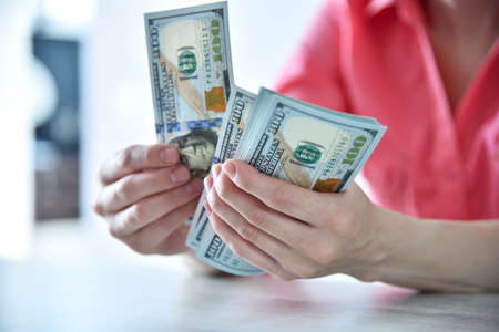 Trader woman hands counting US dollars cash in office. Financial success and business concept. close...