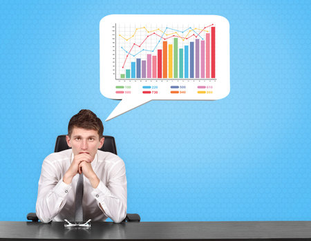 Businessman sitting at the desk and thinking with speech bubble with chart.の写真素材
