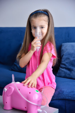 Little girl with inhaler and pink piggy bank. Health care and medical concept.の写真素材