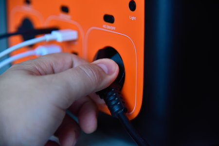 Hand connects power adapter to portable charging station. Backup energy and technology concept. Close upの写真素材