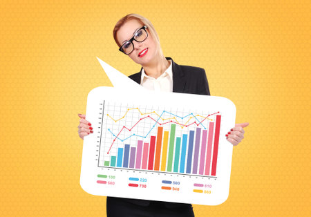 Businesswoman holding a speech bubble with stock chart on it over yellow backgroundの写真素材