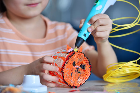 Child using a 3D pen to craft a colorful structure, focused on creativity and innovation in art. Close upの写真素材
