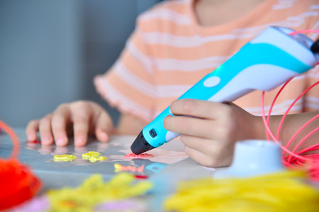 Little girl diligently making invention with 3D pen. Creativity and innovation in art concept. Close upの写真素材