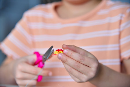Girl cuts off extra parts from 3D toy with scissors. Creativity and innovation in art concept. Close upの写真素材