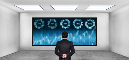 Businessman looking to business big data with stock charts on digital screen. Concrete dark room. Virtual reality and global networking concept.の写真素材
