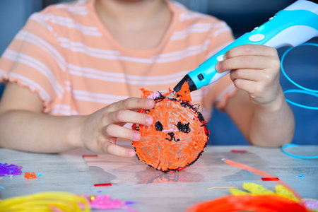 Girl drawing with stylish 3D pen at table indoors. Concept of creativity and innovation in art.の写真素材