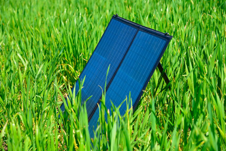Foldable portable solar panel placed in tall green grass, natural lighting, eco-friendly energy concept, renewable power in outdoor settingの写真素材