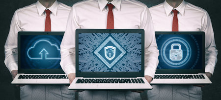 Three business professionals holding laptops displaying cybersecurity and cloud computing graphics,...