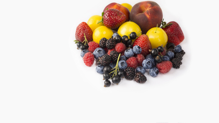 Ripe blueberries, raspberries, black currants, blackberries, strawberries, yellow plums and peaches on white background. Berries with copy space for text. Background berries. Various fresh summer berries.の写真素材