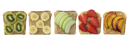 Sandwiches with peanut butter and fruits isolated on white background. Fresh healthy appetizer snack with bread. Sandwiches on bread topped with fresh strawberry, banana, apple, nectarine and kiwi. Healthy breakfast with toasts. Top view.の写真素材