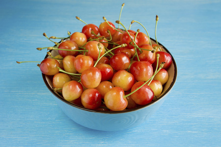 A bowl cherries on a blue backgroundの写真素材