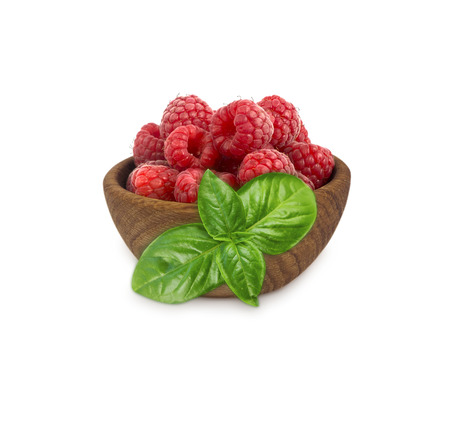 Raspberries in a wooden bowl isolated on white background. Raspberry with basil close-up. Vegetarian...