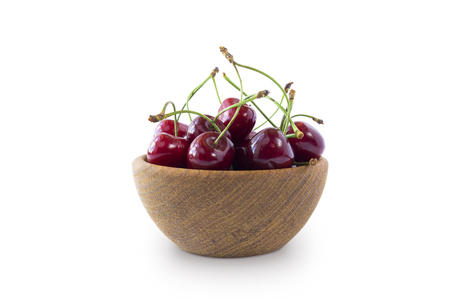 Sweet cherry berries in wooden bowl isolated on white background cutout. Cherry fruit in a wooden bowl with copy space for text.の写真素材