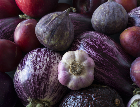 Background of fresh vegetables and fruits. Purple eggplant, plums, figs, apples and garlic. Top view. Purple food.の写真素材