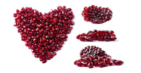 Heart shape pomegranate seeds on white background. Pomegranate seeds isolated on white background. Background made of red pomegranate seeds. The scattered red grains of granate. Garnet with copy space for text. Top viewの写真素材
