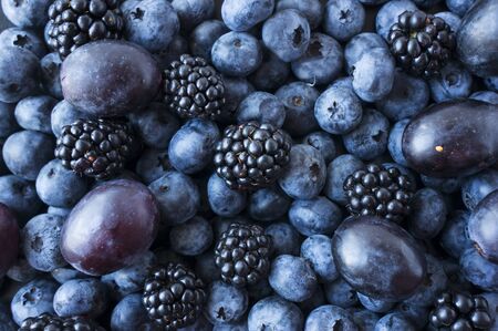 Texture berries close up. Top view. Black and blue berries. Ripe blueberries, blackberries and plums. Various fresh summer berries. Mix berries. の写真素材