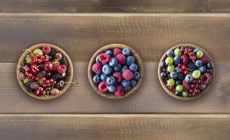 Top view. Fruits and berries in bowls on wooden background. Mixed fruits with copy space for text. Mixed berries on wooden background. Various fresh summer berries and fruits.の写真素材