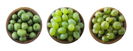 Green food isolated on a white background. Collage of different fruits and berries at green color. Green baby kiwi fruit actinidia, gooseberry and green grapes in a wooden bowl. Green fruit and berry.の写真素材